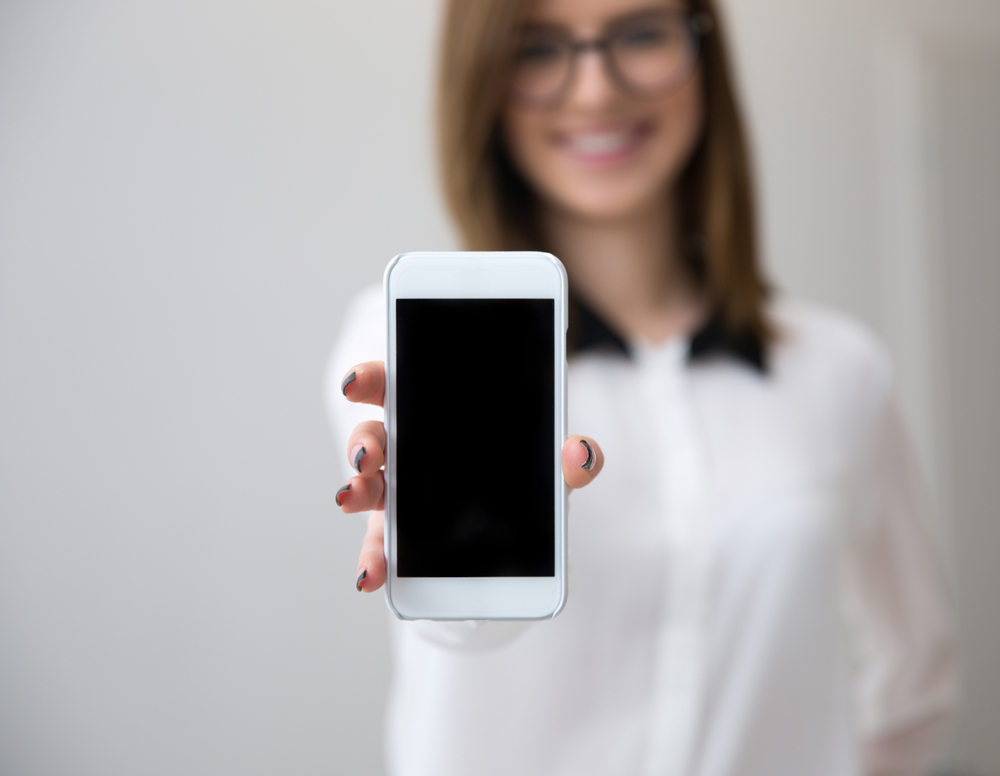 Businesswoman showing a blank smartphone screen. Focus on smartphone